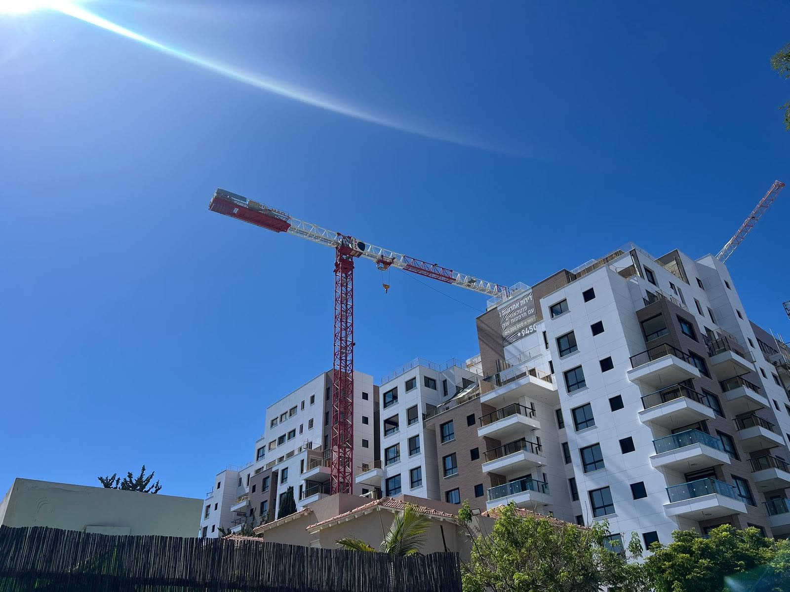 עגורן צריח אדום לצד בניין מגורים לקראת סיום