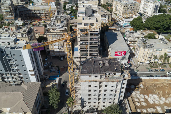 עגורן צריח ממוקם בין בנייני מגורים בפרויקט התחדשות עירונית ברחובות